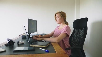 beautiful young woman working on a laptop and computer while sitting at a desk.