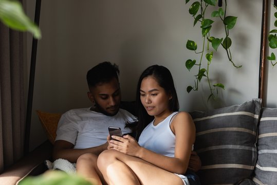 Couple using mobile phone on sofa in living room