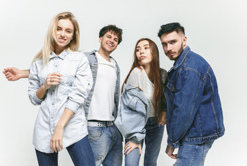 Obraz premium Group of smiling friends in fashionable jeans. The young men and woman posing at studio. The fashion, people, happy, lifestyle, clothes concept