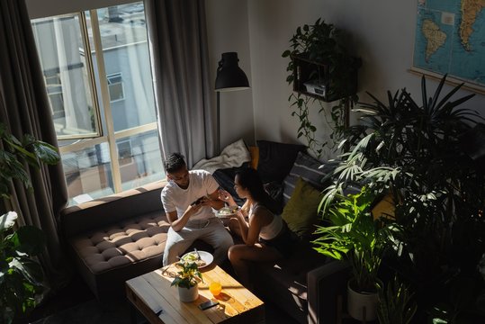 Man taking photo of woman having food with mobile phone in