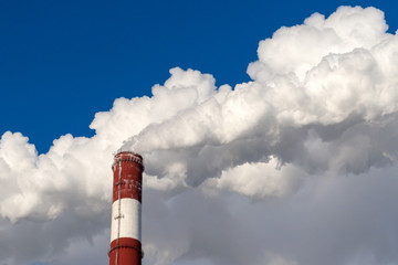 Upper part of the smoking pipe of a power plant against a blue sky.