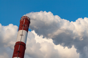 Upper part of the smoking pipe of a power plant against a blue sky.