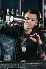bartender making French 75 Cocktail pouring fluid into glass. Bar on a background