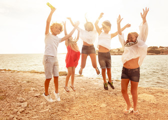 Obraz premium Cute teens jumping together on the beach in summer