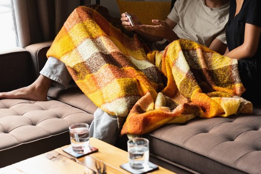 Couple using mobile phone on sofa in living room at home