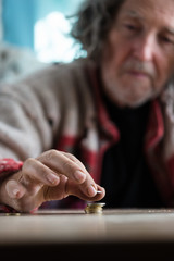 Senior homeless man stacking coins