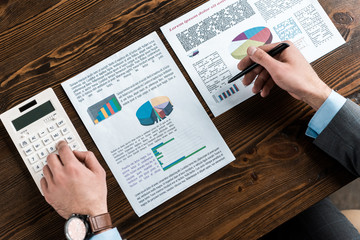 cropped shot of businessman doing paperwork with calculator at workplace