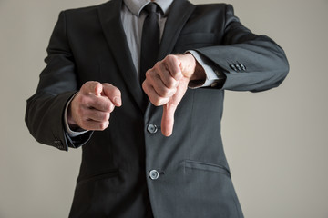 Businessman pointing at you and showing a thumbs down sign