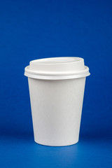 Paper coffee container with white lid on blue background. Take-away beverage container. Drink Cup template for your design