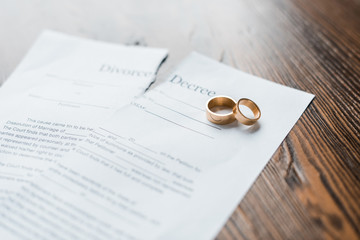 close-up shot of teared divorce decree and engagement rings on wooden table