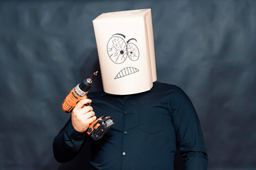 Emotion concept. A man holds an hand drill in front in front of. On the face, an expression of anger and determination.