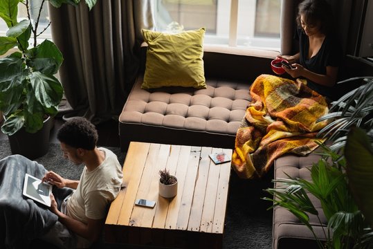 Couple using mobile phone and digital tablet while having coffee