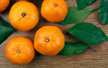 bunch of fresh tangerines or mandarins on a wooden table and leaves