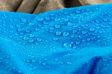 Nylon waterproof fabric background with blurred foreground. Rain Drops on Water Resistant Textile...