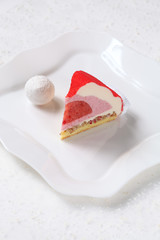 Piece of Contemporary Strawberry Mousse Cake, on white plate, on white background.