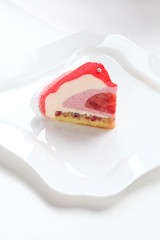 Piece of Contemporary Strawberry Mousse Cake, on white plate, on white background.