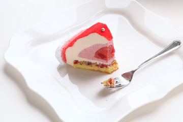 Piece of Contemporary Strawberry Mousse Cake, on white plate, on white background.