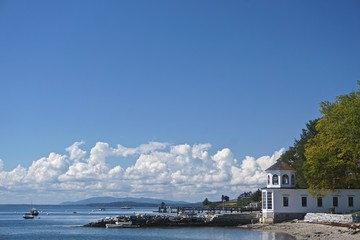 Castine, Maine, USA: Beautiful white clouds in a blue sky over the harbor at Castine, with small boats in Penobscot Bay and mountains in the distance.