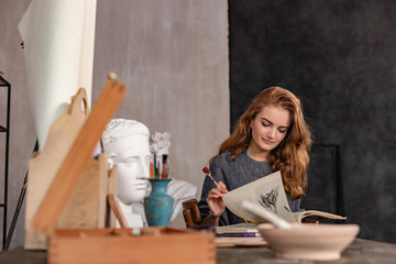 Portrait of a gorgeous female artist working on art project on her studio
