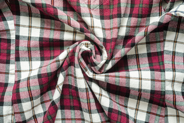 Wrinkled plaid fabric. Background crumpled cloth in a cage. Twisted in the center cloth swatch
