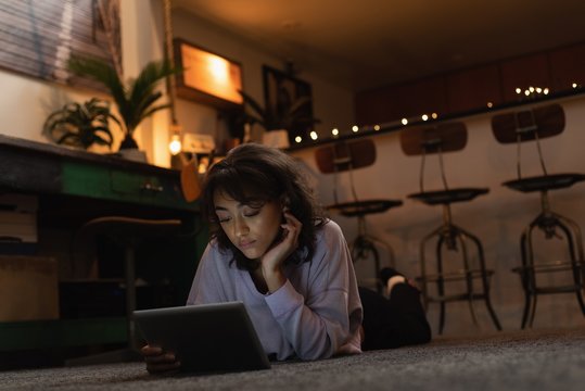 Woman using digital tablet on floor at home