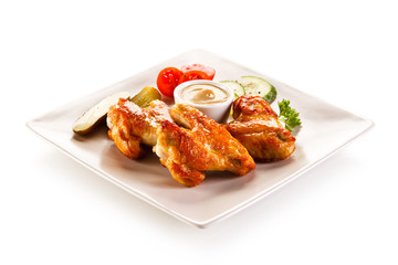 Grilled chicken wings with vegetables on white background