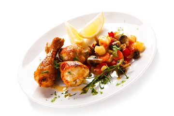 Grilled chicken drumsticks with vegetables on white background