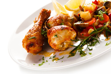 Grilled chicken drumsticks with vegetables on white background
