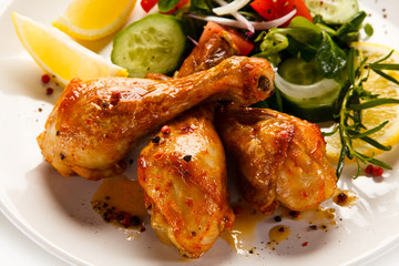 Grilled chicken drumsticks with vegetables on white background