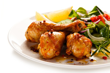 Grilled chicken drumsticks with vegetables on white background