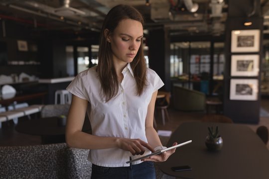 Woman using digital tablet while standing in cafeteria