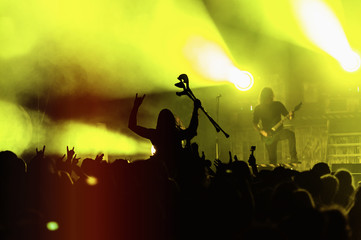 Silhouette of a young man with crutches on top of a crowd enjoying in concert