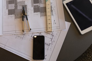 Blueprint, compass, mobile phone and digital tablet on a table