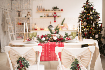 Interior light kitchen and red christmas decor. Preparing holiday dinner at home on the kitchen concept. Decorated new Year fir. Selective focus