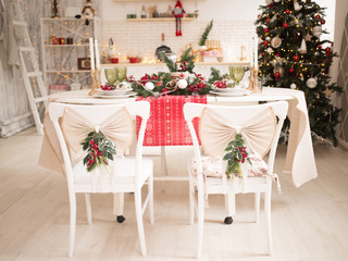 Interior light kitchen and red christmas decor. Preparing holiday dinner at home on the kitchen concept. Decorated new Year fir. Selective focus