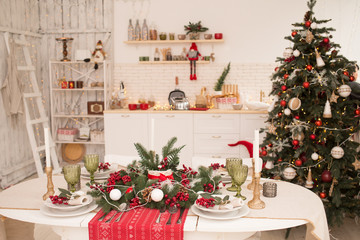 Interior light kitchen and red christmas decor. Preparing holiday dinner at home on the kitchen concept. Decorated new Year fir. Selective focus