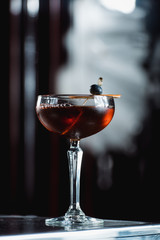 The Boulevardier Cocktail with orange chips on top. On a bar desk