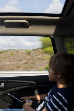 ni&ntilde;o viajando dentro de un coche mirando paisaje por la ventanilla
