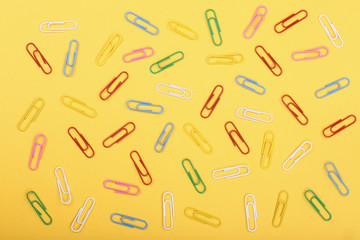 colorful paper clips on yellow background. Top view. Flat lay pattern