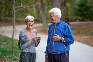 Older couple jogging in the park with distance tracker watch on hands and smile
