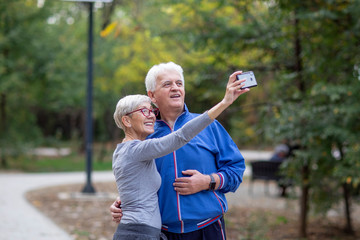 Mature couple taking selfie by mobile phone after jogging at the park
