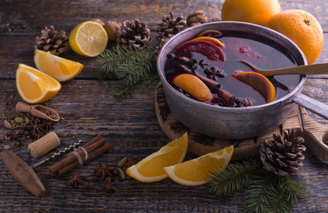Hot alcohol christmas homemade drink mulled wine in a pan with species on a wooden background, copy space.
