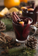 Homemade Christmas traditional hot drink in glass mug with species and orange on a wooden...