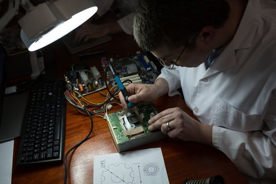 Robotics engineer assembling circuit board at desk