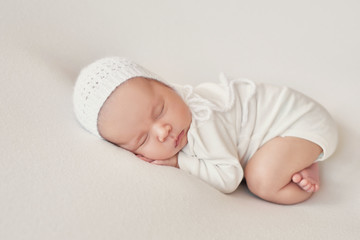 Cute newborn baby girl lies swaddled in a white blanket. Baby goods packaging template. Closeup portrait of newborn baby with smile on face. Healthy and medical concept. 