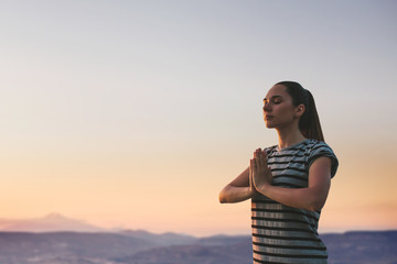 A girl practices yoga or meditation or searching for a soul against the backdrop of a beautiful sunset. Solitude and unplugged