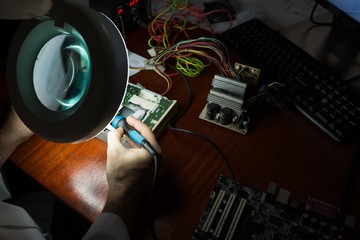 Robotics engineer assembling circuit board at desk