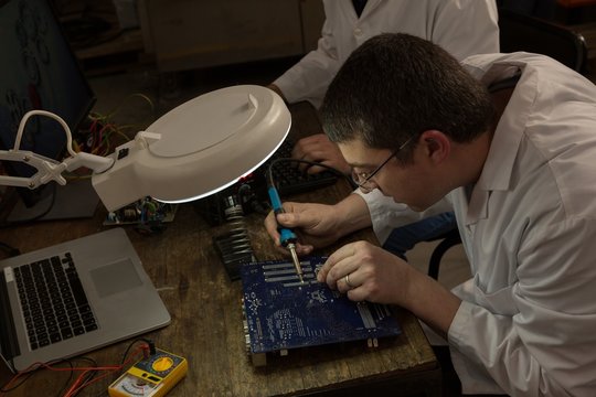 Robotics engineer assembling circuit board at desk