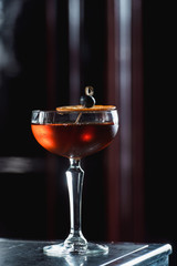 The Boulevardier Cocktail with orange chips on top. On a bar desk