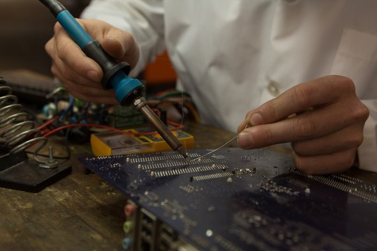Robotics engineer assembling circuit board at desk
